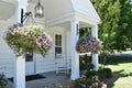 Hanging Baskets Of Pink And Purple Flowers Framing A Porch With White Rocking Chair.