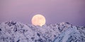 Full moon rising over a winter mountain landscape