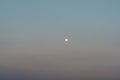 View of the full moon setting over the suburbs at night.