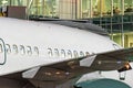 View of the fuselage of a passenger aircraft with portholes on the background of the airport`s glass terminal at night. Royalty Free Stock Photo