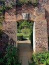 A view through a gateway in a red brick wall to a garden beyond. Royalty Free Stock Photo