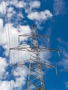 View of giant power tower with high voltage power cables against clear blue sky with white clouds Royalty Free Stock Photo