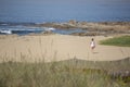 View at a girl, alone and walking on the beach of Leca da Palmeira, Portugal