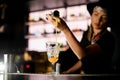 View of girl bartender pours syrup from jigger to cocktail glass at bar counter