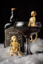 View of glass of black widow Halloween cocktail with skeleton and bottle of poison on spider web,