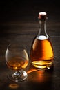 View of glass of cognac and a bottle aside on color wooden