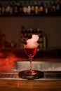 view of glass with foamy cocktail decorated with red berry and small heart on the bar