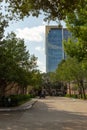 View of a glass skyscraper office building from an in town city street with a white cloud blue sky background