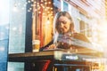 View through glass. Young smiling business woman sitting in cafe at table, drinking coffee and using tablet computer. Royalty Free Stock Photo