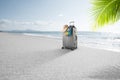 Suitcase with pareo and hat on tropical beach