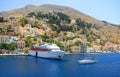 View on Greek sea Symi island port harbor classical ship yachts, houses on island hills, tourists Aegean Sea bay. Greece islands