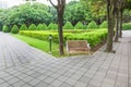 View of green garden with a small square and wooden bench for resing in the corner of the city park Royalty Free Stock Photo