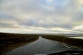 View on grey road, yellow surise and dramatic clouds from the car front window in early mourning. Driving car during sunshine in Royalty Free Stock Photo