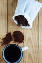 FRESH BLACK COFFEE IN A MUG WITH GROUNDS ON A WOODEN BOARD AND ROASTED BEANS IN A WHITE LINEN BAG Royalty Free Stock Photo