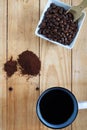 FRESH BLACK COFFEE IN A MUG WITH GROUNDS ON A WOODEN BOARD AND ROASTED BEANS IN A CERAMIC BOWL Royalty Free Stock Photo