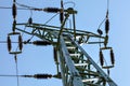 View from ground to power pylon top. Cables and ceramic isolators visible against blue sky. Abstract power industry background Royalty Free Stock Photo