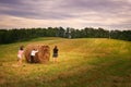 View of a group of young girls attempting to roll a round hay bale in a field Royalty Free Stock Photo