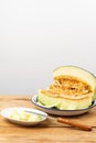 View of half green melon in white plate on wooden table, with pieces of melon and knife, selective focus Royalty Free Stock Photo