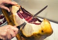 Hand and knife slicing Spanish ham