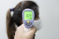 View of Hand Using Infrared Thermometer Gun Checking Woman Forehead for Body Temperature tp Protect from Corona Virus