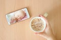 View handheld color video baby monitor. Female hands are holding a smartphone with a baby monitor app. Near hot drink Royalty Free Stock Photo