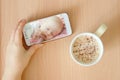 View handheld color video baby monitor. Female hands are holding a smartphone with a baby monitor app. Near hot drink Royalty Free Stock Photo