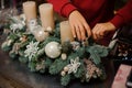 view of hands of florist woman who decorates r composition of fir branches and candles