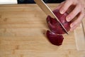 View on hands of a man chopping and peeling a fresh red onion for lunch an a bamboo cutting board. Royalty Free Stock Photo