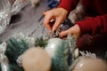 View on hands of woman who decorates fir branches with gilded branches