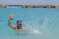 View of happy man with cocktail glass in his hand in splashing ocean water.