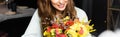 View of happy woman with bouquet of autumn flowers in cafe Royalty Free Stock Photo