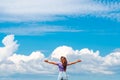 View of a happy young woman jumping on a summer meadow in the air against a blue sky with clouds Royalty Free Stock Photo