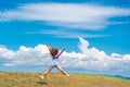 View of a happy young woman jumping on a summer meadow in the air against a blue sky with clouds Royalty Free Stock Photo