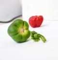 View of a headless, shiny green bell pepper next to a headless red bell pepper on a white background with lighting and shadows Royalty Free Stock Photo