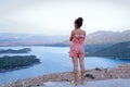 A girl looks from a height at the river.A young girl stands near a cliff, and looks down.View from the height of the river