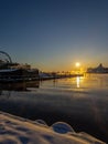 A view of Helsinki harbour and ferris wheel at sunset as seen from snow covered Allas Sea Pool
