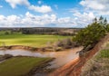 View from the high bank at the river bend and grassy plain. Shadows of clouds running across the plain