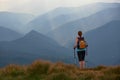 The view with the high mountains in fog. The sun rays are enlighten the forests. The extreme girl with the tracking sticks. Royalty Free Stock Photo