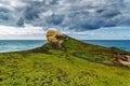 View of high sandy cliff covered with grass and waves of Pacific ocean at Tunnel beach