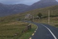 View of a highway winding through rural Connemara in western Ireland at dusk with mountains in the background
