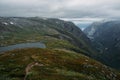 view of hill slope with grass and small pond, mountains on background, Norway, Hardangervidda