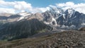 View from the hill top of endless snow capped mountain range. Clip. Breathtaking wild nature with clouds floating above