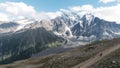 View from the hill top of endless snow capped mountain range. Clip. Breathtaking wild nature with clouds floating above