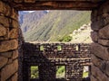 View of a hillside in Machu Picchu, Peru, seen from a window built with stone and wood.