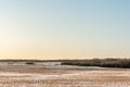 View of a hilly horizon with a snow-covered field with orange dry grass and shrubs. Clear blue orange sky in early spring in Royalty Free Stock Photo