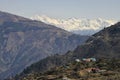 View of a Himalayan village on slop of mountain and snow capped mountain ranges