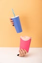 View of holes and woman holding bucket with popcorn and disposable cup with soft drink on orange and white