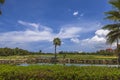 View of hotel building and blue water surface of pond and green grass golf field on background blue sky with white clouds. Royalty Free Stock Photo