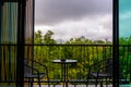 View from hotel room window with balcony to tropical forest during the storm with rain. Big shadow clouds and rainy weather. Two Royalty Free Stock Photo