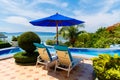 View from a hotel with sun loungers and a parasol in front of the infinity pool on the tropical beach and beautiful sea with boats Royalty Free Stock Photo